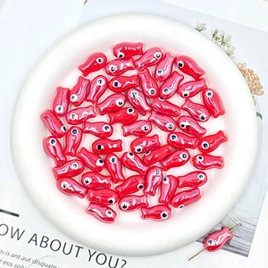 Detailed view of red ceramic fish-shaped beads with glossy finish for DIY jewelry crafts
