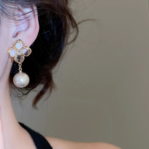 Detail of elegant gold-plated flower stud earring with crystal petals and round white pearl