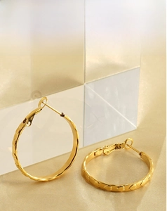 Dettaglio di orecchini a cerchio placcati oro 18k con cuori a rilievo su seta dorata