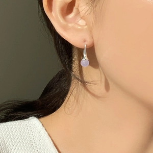 Close-up of lilac bead earrings with silver hooks worn by model in natural soft light
