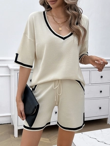 Close-up of beige knit two-piece set with black trim V-neck top and matching shorts