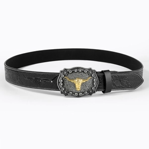 Detail of silver western buckle with golden bull relief on embossed black leather belt