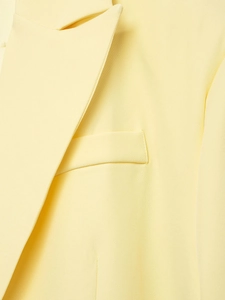 Close-up of pale yellow blazer lapel and pocket detailing with fine woven fabric texture