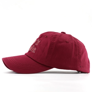 Dettaglio del cappellino in cotone rosso vino con ricamo bianco e cuciture sulla visiera