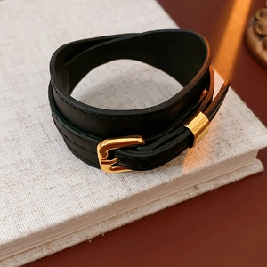 Detail of black double-wrap faux leather bracelet with gold rectangular metal buckle