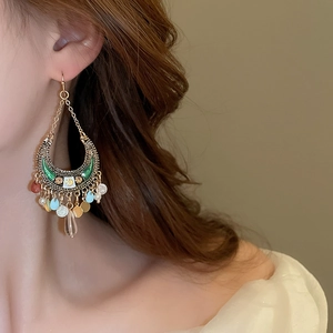 Detail of bohemian moon tassel earrings with colorful sequins worn by a model