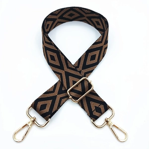 Close-up of geometric diamond pattern embroidery on adjustable woven bag strap with gold hooks