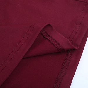 Makro-Detail von weinrotem Kleiderstoff mit hochwertigen Nähten und Textur