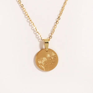 Detail shot of golden titanium oval pendant featuring delicate rose flower engraving