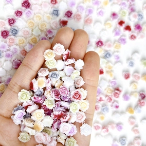 Vista macro di ciondoli per nail art in resina a forma di rose colorate sulle dita