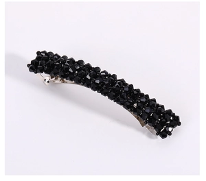 Détail des perles noires facettées tissées à la main sur une barrette à ressort en métal
