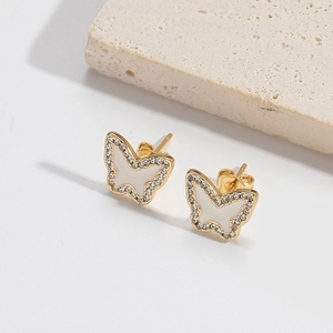 Détail de boucles d'oreilles papillon dorées avec émail blanc et accents de zircons