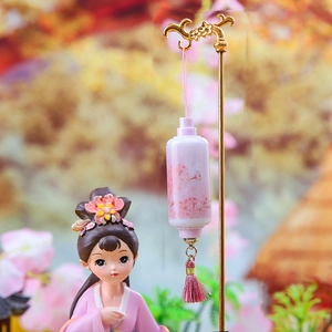 Close-up of a pink lantern with cherry blossoms and a tassel on a golden metal stand