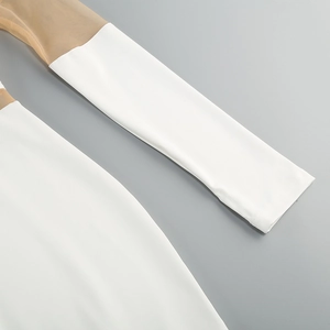 Detail of white long sleeve dress with sheer mesh patchwork and precise stitching