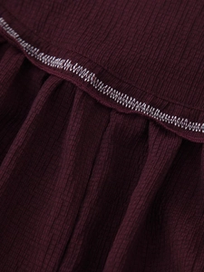 Detailed close-up of burgundy ribbed fabric featuring decorative white zigzag stitching