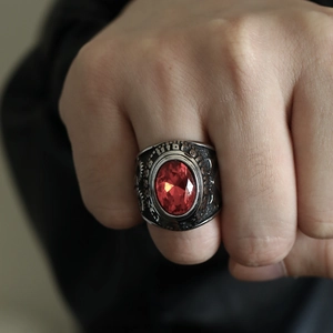 Vista macro de un anillo punk para hombre con gema roja y grabados florales de estilo retro