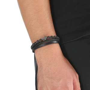 Detail of layered bracelet with black volcanic stone beads, cross charm and leather bands