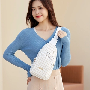 Chic white monogram crossbody bag with gold zippers and wide strap worn by a model