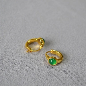 Macro shot of gold brass earrings featuring translucent green agate stones in vintage style