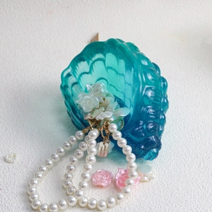 Dettaglio della collana di perle con ciondoli a rosa in un contenitore di resina