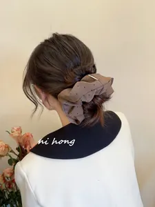 Detailed view of a vintage dark brown scrunchie with tiny polka dots on a ponytail