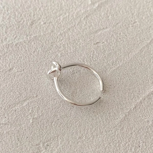 Close-up of a 925 sterling silver open ring with a woven knot design on stone surface