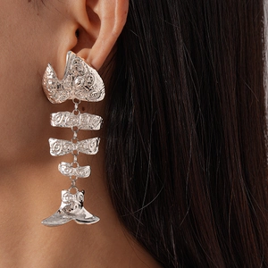 Close-up of silver fishbone earrings with hammered metal texture on model's ear