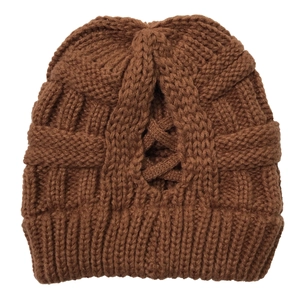 Detail of brown knitted ponytail beanie showing chunky ribbed texture and top opening