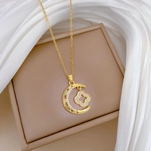 Close-up of a gold moon and four-leaf clover necklace pendant with sparkling zircon accents