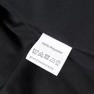 Detail of white clothing care label showing 100% polyester and washing instructions