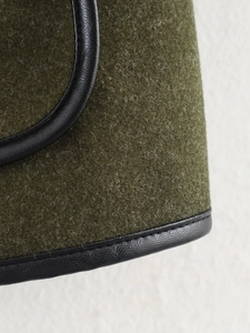 Macro shot of olive green wool fabric with black PU leather piped edges and stitching