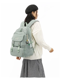 Rear view of a sage green school backpack with cute panda charm on a model