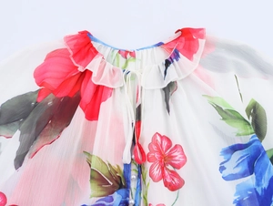 Détail d'une blouse en mousseline fleurie avec col volanté, lien et bouton perle