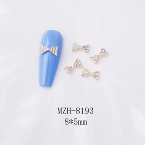 Détail de bijoux de nœuds dorés 8x5mm pour nail art avec strass sur tissu en soie blanc