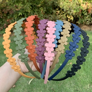 Close-up of matte flower headbands in multiple candy colors on a natural grass background