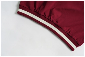 Close-up of burgundy ribbed cuff with white stripe detail on athletic sweatshirt
