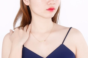 Close-up of minimalist gold bar necklace with small red heart stone on a model neck