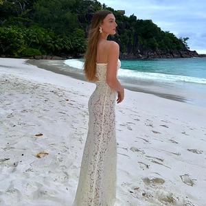Détail de la dentelle florale blanche sur une robe de plage sans bretelles face à la mer bleue