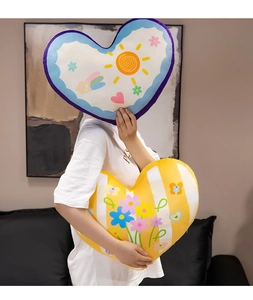 Macro shot showing plush heart pillows with cute cartoon sun and flower patterns