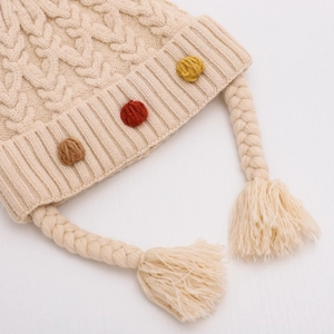 Dettaglio ravvicinato del cappello lavorato a maglia per neonati con pompon colorati