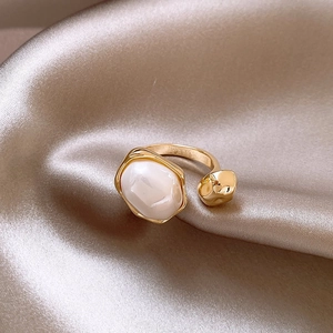 Detail of vintage irregular gold ring with pearl on champagne silk background