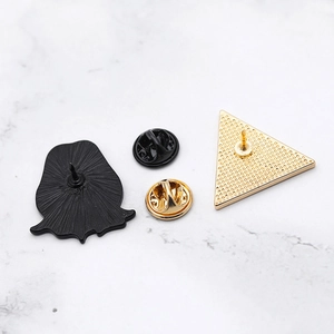 Detailed view of enamel pins featuring a black ghost and golden triangle with metal backings
