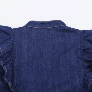 Détail du col de chemise en jean bleu foncé avec épaule à volants et coutures dorées