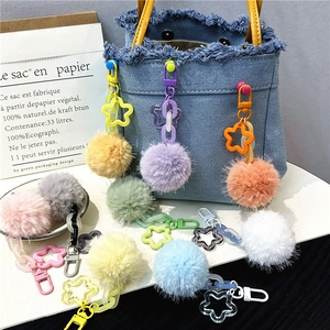 Colorful pompom flower keychain with star-shaped clasp shown on a denim bag strap