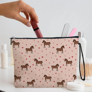 Rosa Canvas-Kosmetiktasche mit Pferdemuster, gefüllt mit Lippenstift auf weißem Tisch