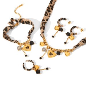 Golden jewelry set with leopard print heart charms and black stones on white background