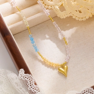 Macro shot of colorful beads and gold heart pendant on a lace-decorated jewelry box