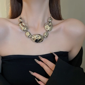 Close-up of modern irregular silver-tone polished necklace on model with black outfit