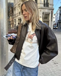 Street style view of a brown faux leather jacket styled with a white tee and blue denim jeans