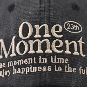 Washed dark gray baseball cap featuring One Moment embroidery and 23th circular logo